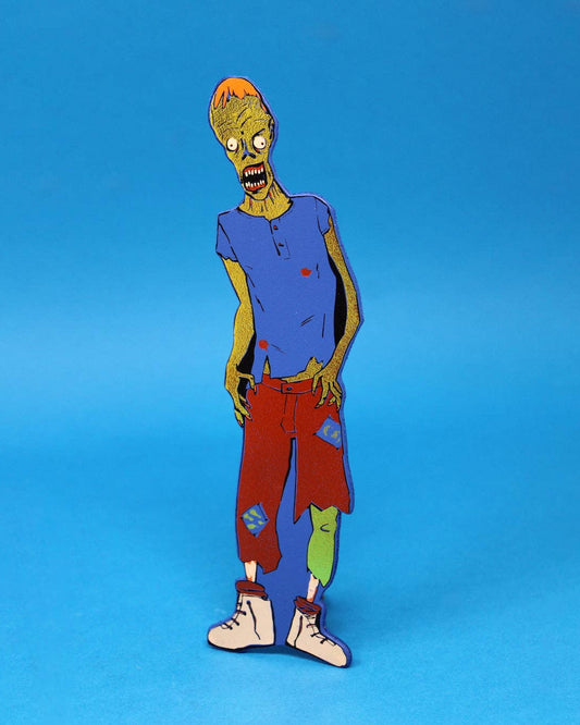 A leather bookmark shapes like a zombie character, standing upright against a solid blue background.