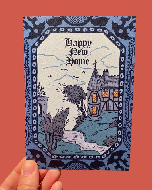 Greeting card with 'Happy New Home' text and gothic/haunted house illustration on a decorative border. 