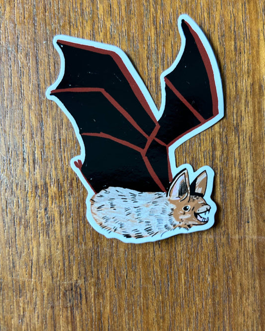 Sticker of a bat wings and furry body, on a wooden surface
