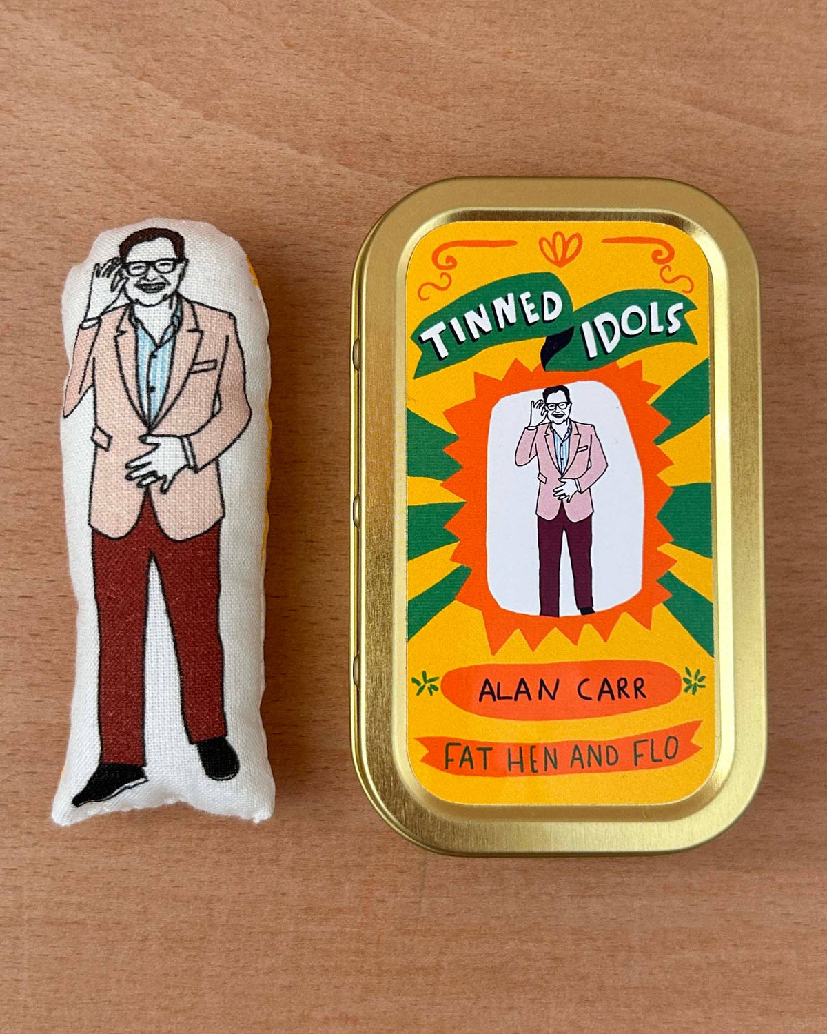 Small plush toy of a man and its packaging on a wooden surface